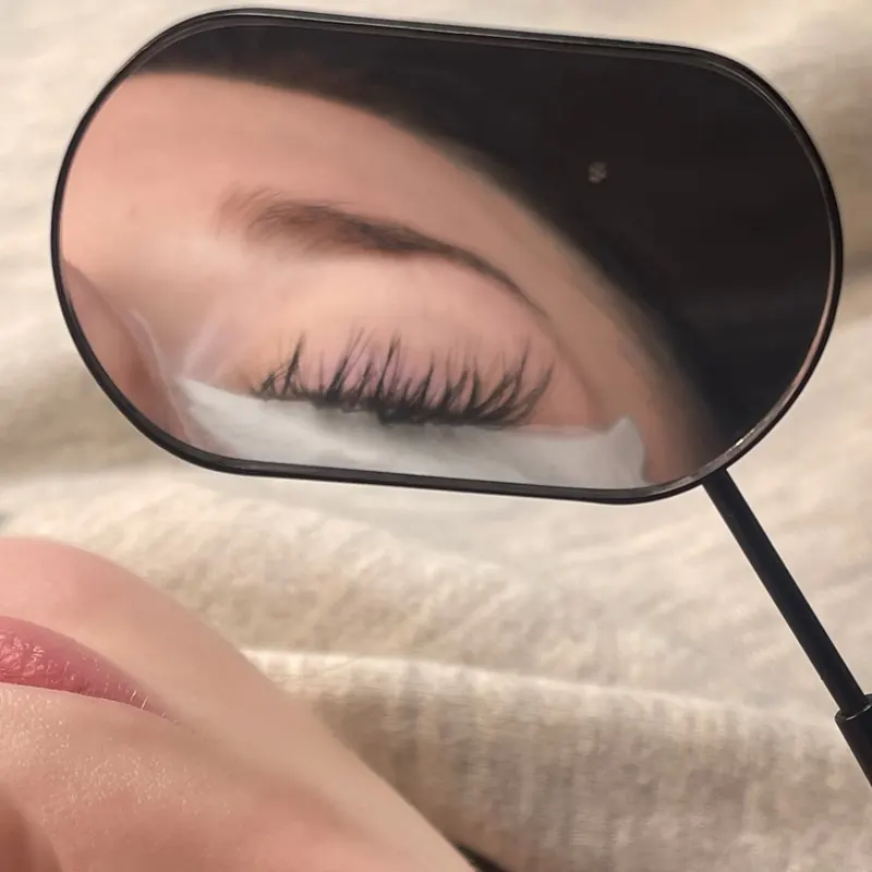 Client checking her new lash set in a hand mirror